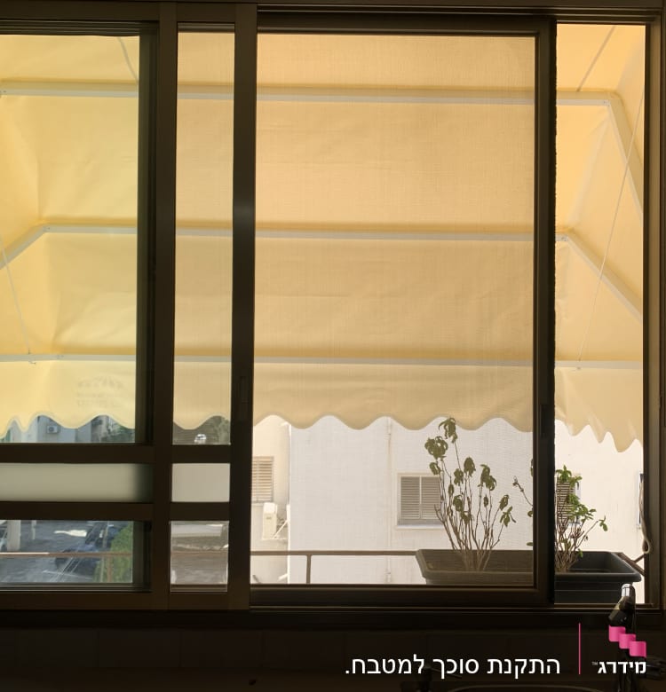 סוכך צהוב מחוץ לחלון עם מסגרת מתכת